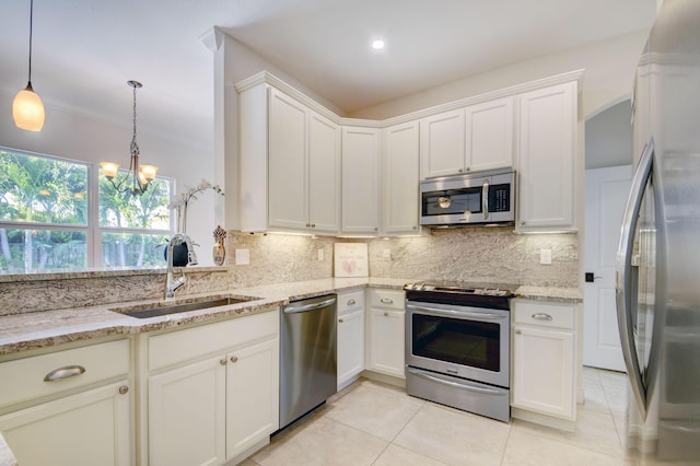 kitchen featuring light tile patterned floors, stainless steel appliances, decorative backsplash, a sink, and light stone countertops