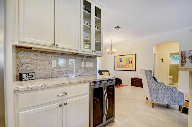 kitchen with arched walkways, wine cooler, visible vents, backsplash, and crown molding