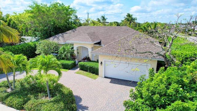 view of front of home featuring a garage, roof with shingles, decorative driveway, and stucco siding