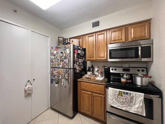 700 Scotia Dr Unit 103, Hypoluxo, FL 33462 - kitchen featuring stainless steel appliances, brown cabinets, visible vents, and a textured ceiling