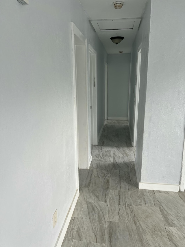 hall featuring attic access, marble finish floor, and baseboards