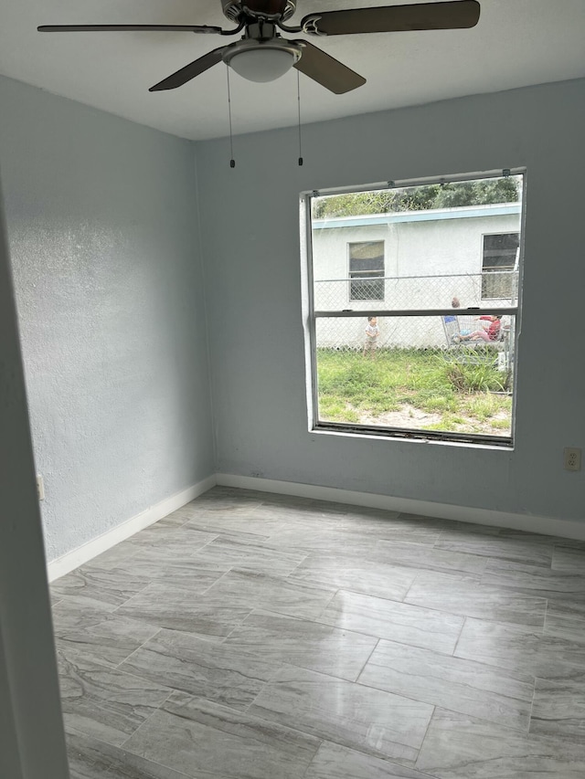 unfurnished room featuring a wealth of natural light and baseboards