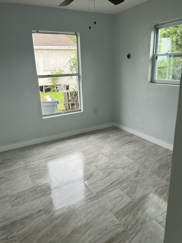 unfurnished room with a ceiling fan and baseboards