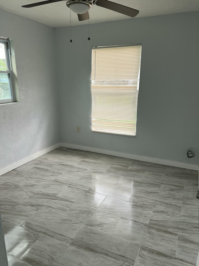 unfurnished room with ceiling fan and baseboards