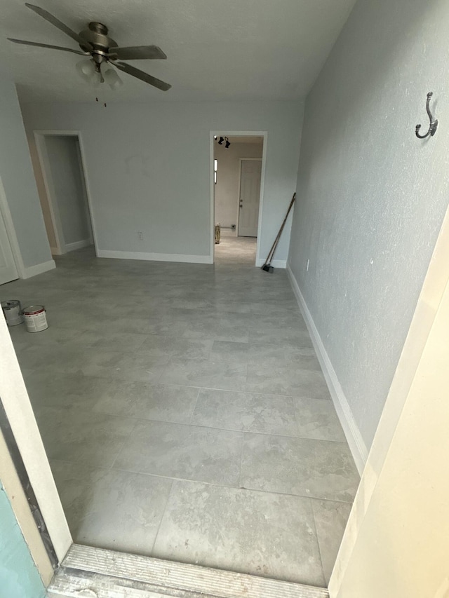 interior space with a ceiling fan and baseboards