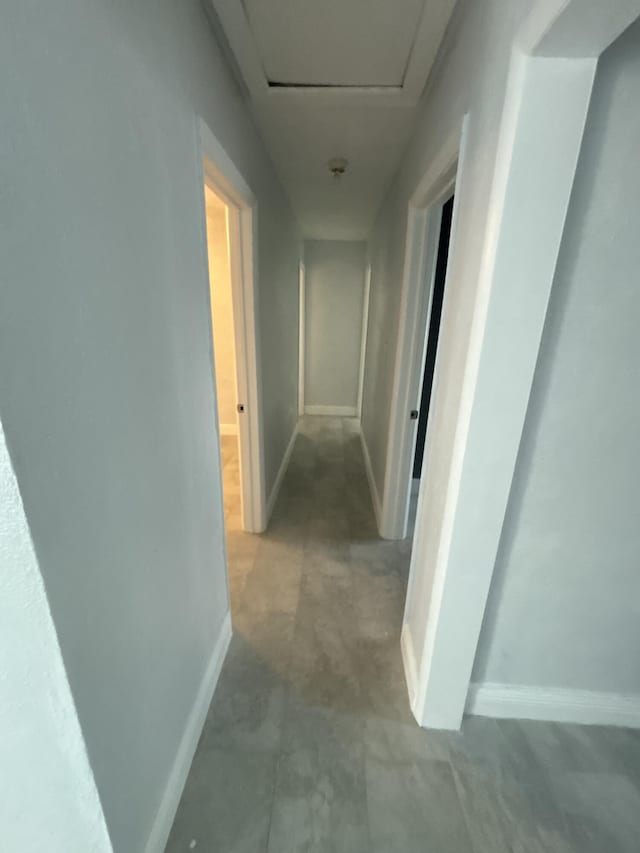 hallway with attic access and baseboards