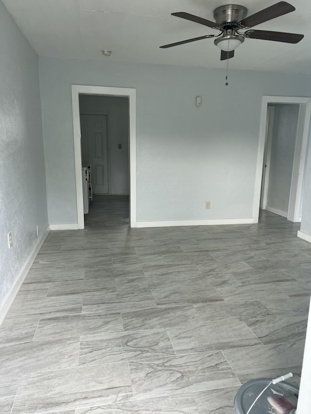 empty room featuring ceiling fan and baseboards