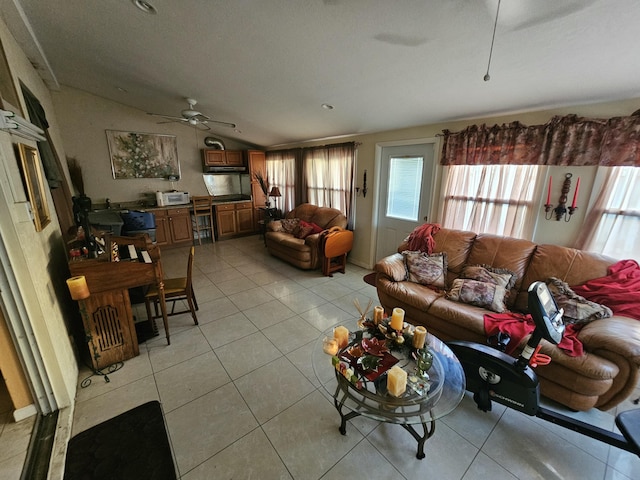 living area with lofted ceiling, ceiling fan, and light tile patterned floors