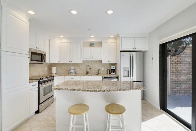 kitchen with a sink, stainless steel appliances, tasteful backsplash, and light tile patterned floors