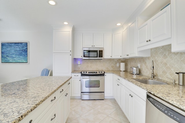 kitchen with tasteful backsplash, light tile patterned floors, light stone counters, appliances with stainless steel finishes, and a sink