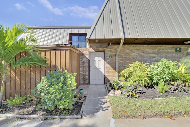 entrance to property with brick siding, a gate, and fence