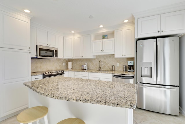 kitchen featuring decorative backsplash, white cabinets, appliances with stainless steel finishes, and a sink