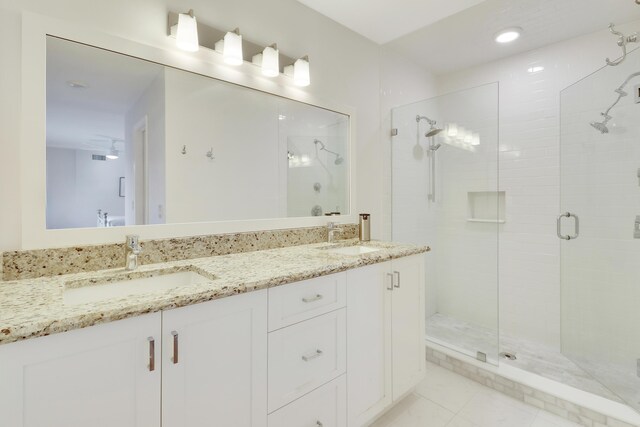 full bath with double vanity, a stall shower, tile patterned floors, and a sink