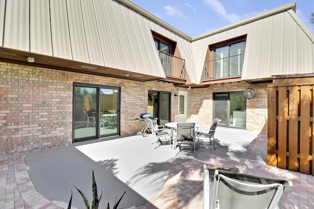 view of patio with outdoor dining space, a balcony, and visible vents