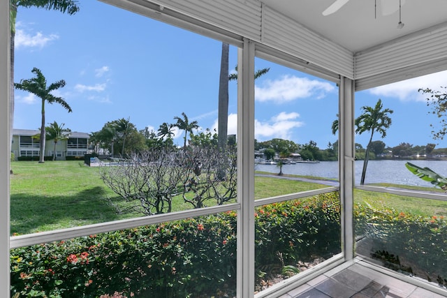 unfurnished sunroom featuring a ceiling fan and a water view