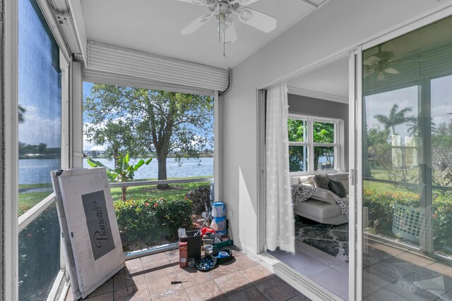 sunroom featuring a water view and a ceiling fan