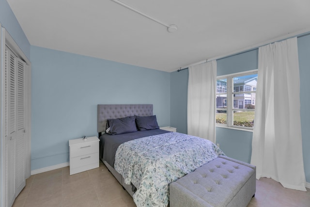 bedroom featuring a closet, baseboards, and light tile patterned floors