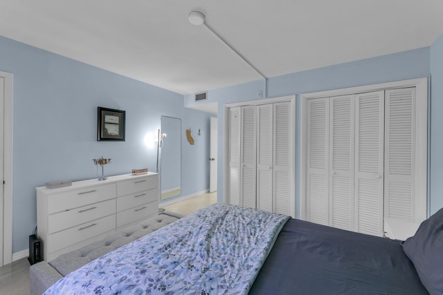 bedroom featuring baseboards, visible vents, and multiple closets