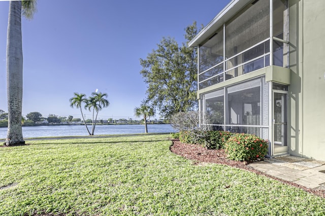 view of yard featuring a sunroom and a water view