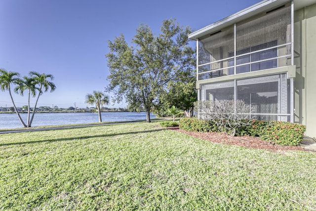 view of yard featuring a sunroom and a water view