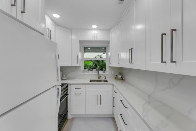 kitchen featuring black / electric stove, a sink, white cabinetry, marble finish floor, and freestanding refrigerator