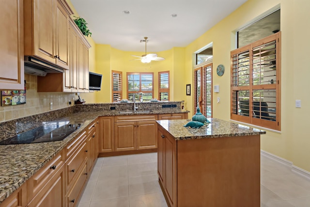 kitchen featuring tasteful backsplash, light tile patterned floors, a sink, and black electric cooktop