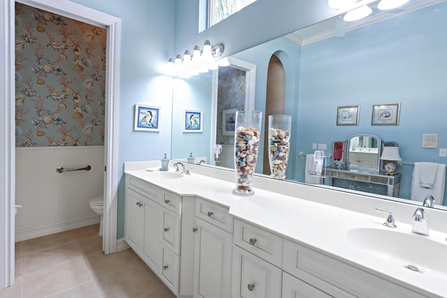 full bathroom with wainscoting, a sink, toilet, and tile patterned floors