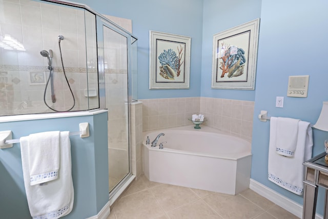 bathroom featuring a garden tub, a shower stall, baseboards, and tile patterned floors