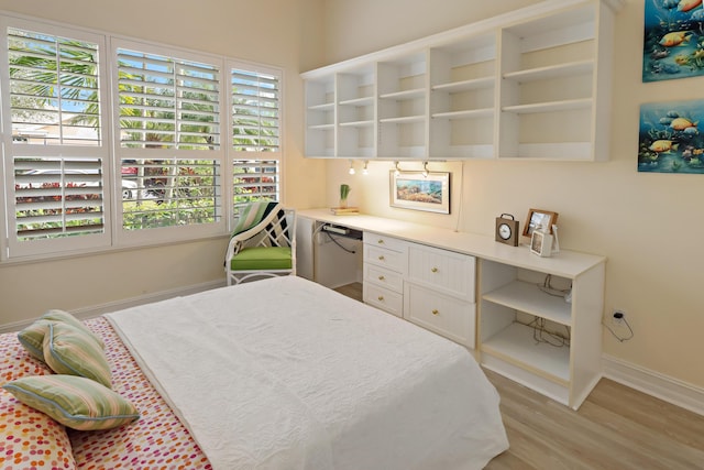 bedroom featuring built in desk, light wood-style flooring, and baseboards