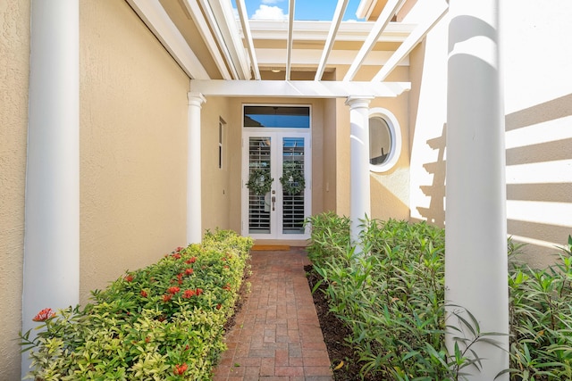 view of exterior entry featuring french doors and stucco siding