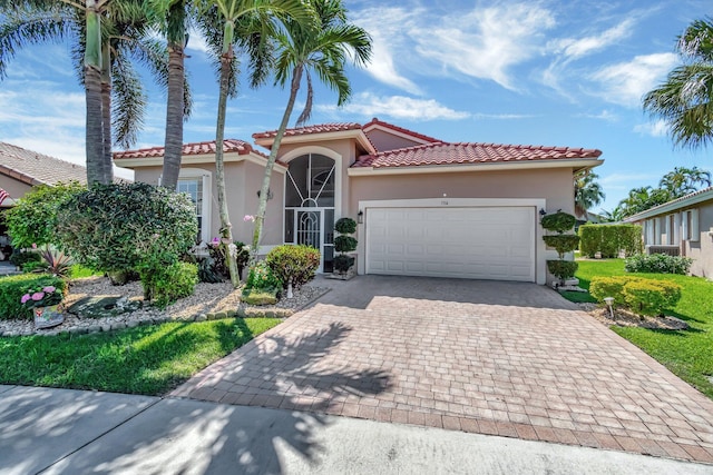 mediterranean / spanish-style house with a garage, a tiled roof, decorative driveway, and stucco siding