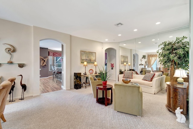 living area featuring arched walkways, visible vents, carpet, and recessed lighting