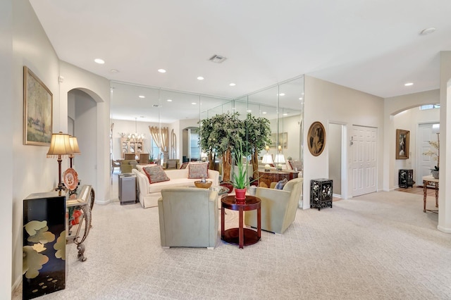 living room with light carpet, visible vents, arched walkways, a notable chandelier, and recessed lighting