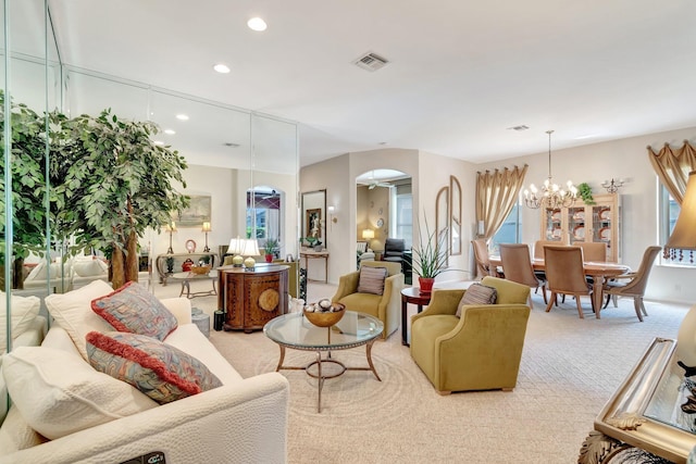 carpeted living area with arched walkways, a notable chandelier, visible vents, and recessed lighting