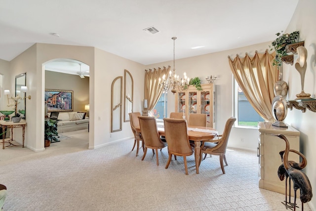 dining area with arched walkways, a notable chandelier, visible vents, light carpet, and baseboards