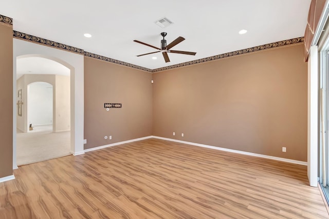 spare room featuring a ceiling fan, light wood-style flooring, arched walkways, recessed lighting, and baseboards