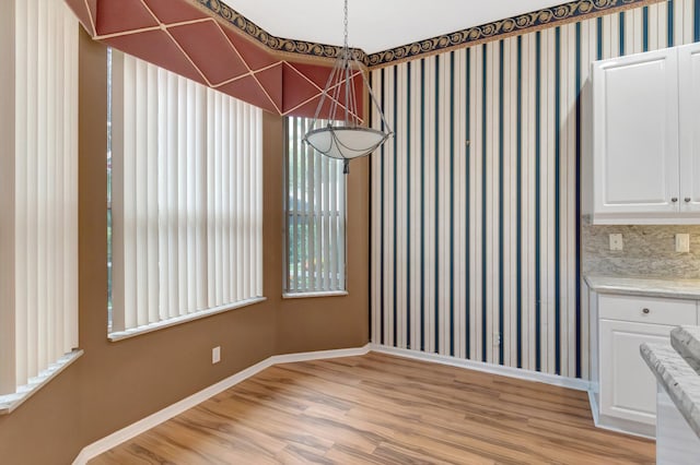 unfurnished dining area featuring light wood finished floors and baseboards
