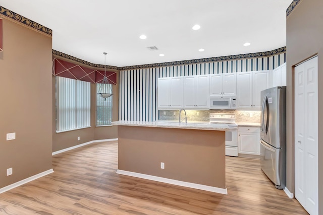 kitchen featuring white appliances, light wood-style flooring, white cabinets, a sink, and a center island with sink