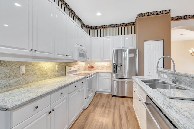kitchen with appliances with stainless steel finishes, a sink, white cabinets, and light wood-style flooring
