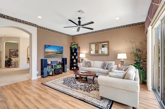 living room with light wood finished floors, baseboards, visible vents, arched walkways, and recessed lighting