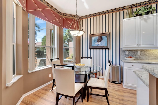 dining space featuring light wood-type flooring, a wealth of natural light, and baseboards