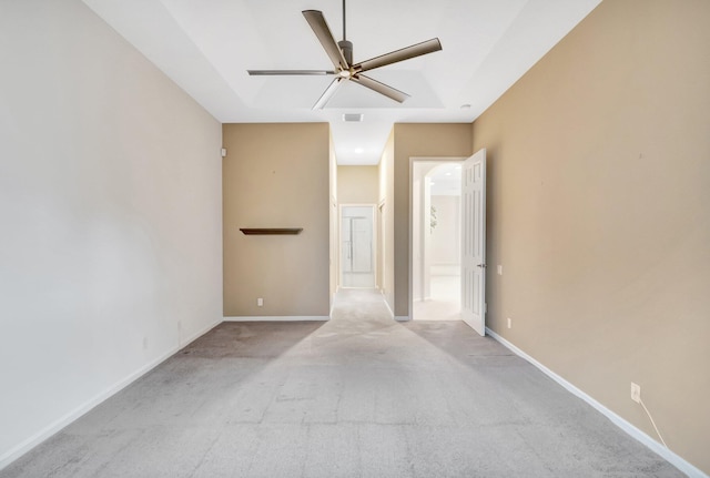 spare room featuring ceiling fan, light colored carpet, and baseboards