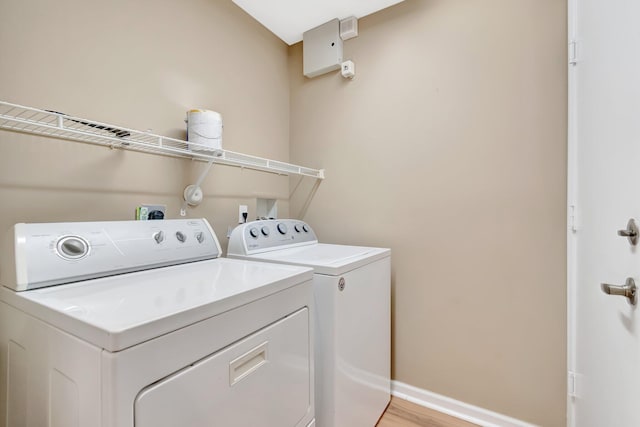 washroom featuring washing machine and clothes dryer, baseboards, and light wood-style flooring