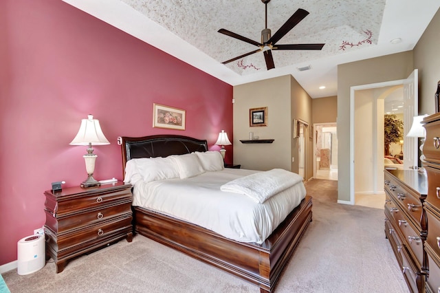 bedroom featuring a raised ceiling, light colored carpet, visible vents, and baseboards