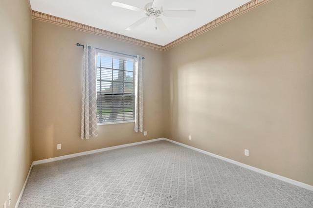 empty room with a ceiling fan, carpet floors, baseboards, and ornamental molding