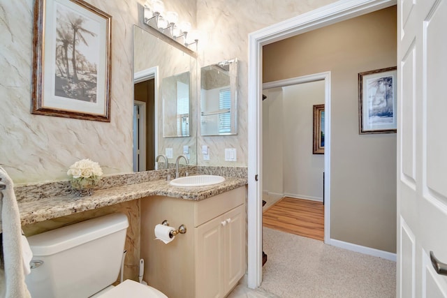 half bathroom with toilet, baseboards, and vanity