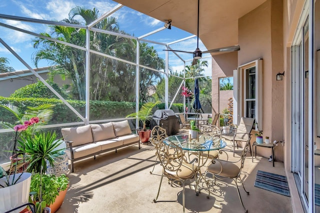 view of patio featuring glass enclosure, outdoor lounge area, and area for grilling