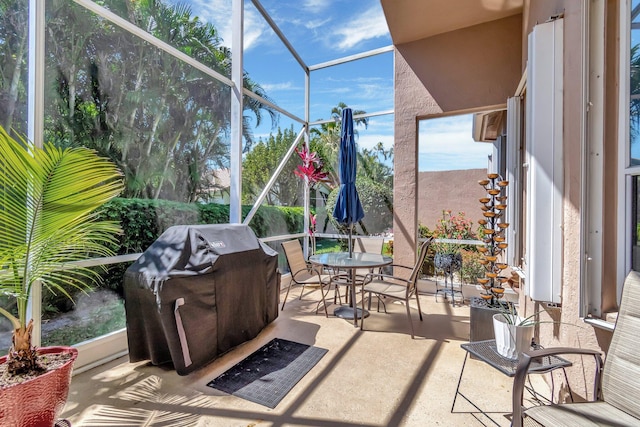 view of patio featuring glass enclosure, a grill, and outdoor dining space