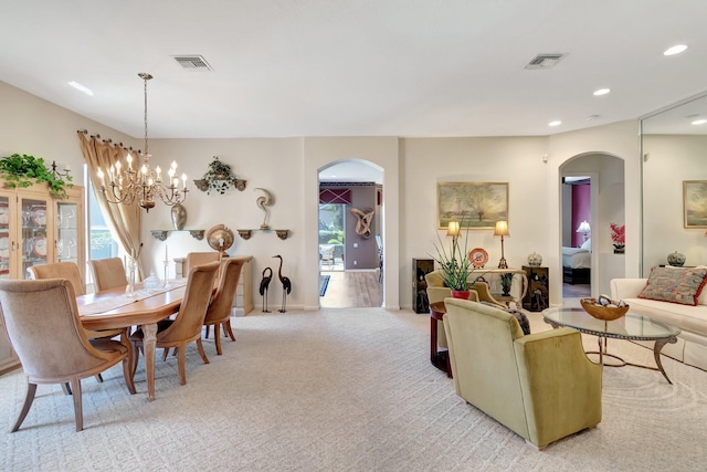 dining room featuring arched walkways, healthy amount of natural light, light colored carpet, recessed lighting, and a chandelier
