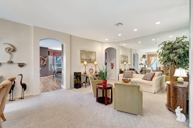 carpeted living room with arched walkways, recessed lighting, and baseboards